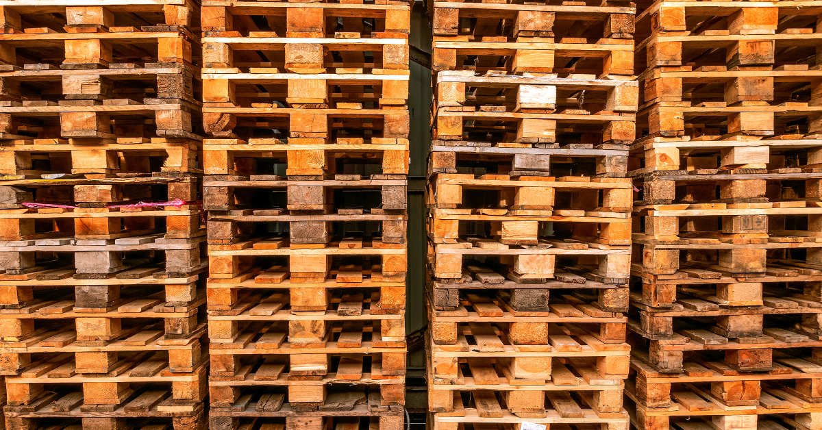 A close-up of several recycled wooden pallets stacked together. The differences in wood grain and cleanliness are visible.