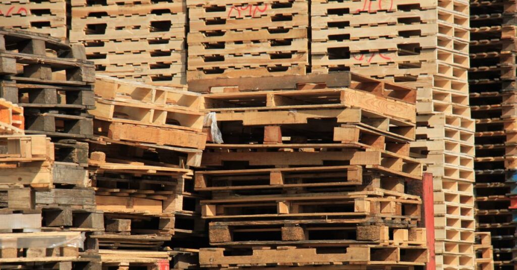 A warehouse yard full of stacks of wooden pallets. Many pallets have wood that varies in texture and color.