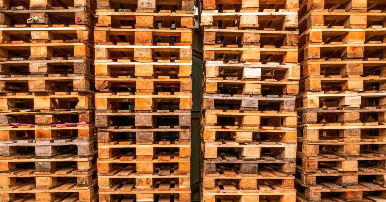 A closeup of several wooden pallets stacked together. Many pieces of wood in the pallets vary in color.