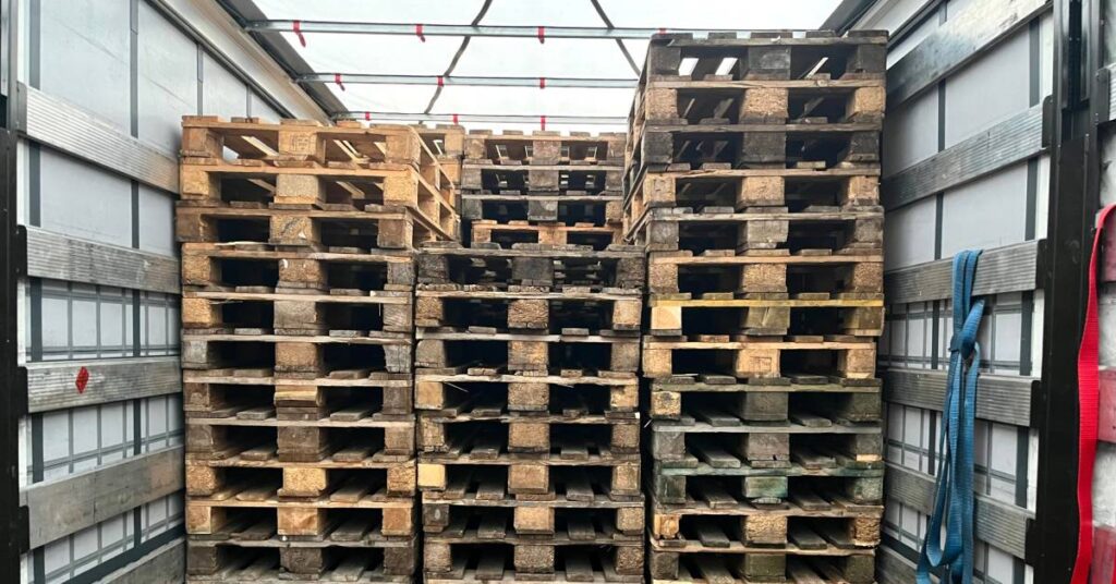 Three tall stacks of wooden pallets that are positioned side-by-side inside of a truck shipping trailer.