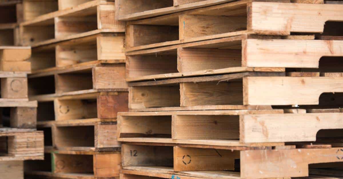 Three tall stacks of wooden pallets feature various stamps of a segmented circle on the inside of the boards.
