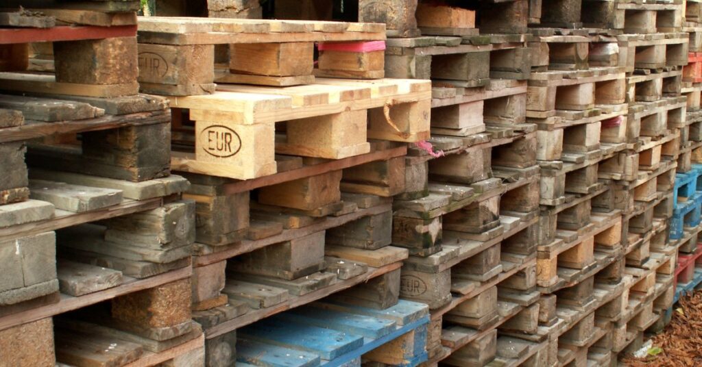 Several neatly organized stacks of pallets. They vary in condition, branding, and even color, but all fit together.