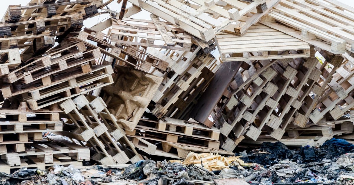 A large landfill pile full of worn down wooden pallets. They're all thrown in a heap rather than evenly stacked together.