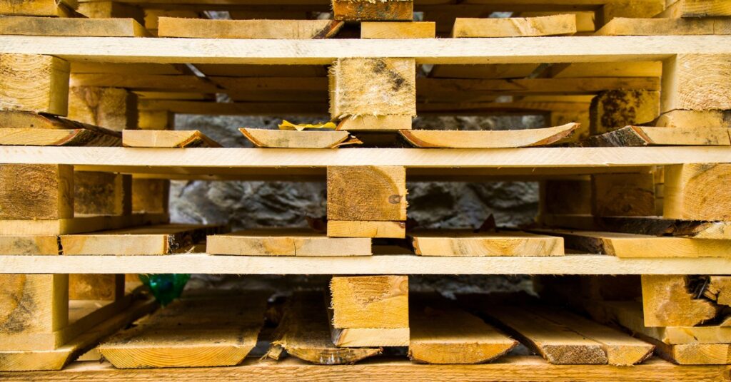 A close-up view of a pile of wooden pallets. Many of the internal boards are somewhat worn down but still stable.